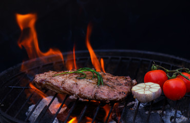 Beef steak on the grill grate, flames on background 