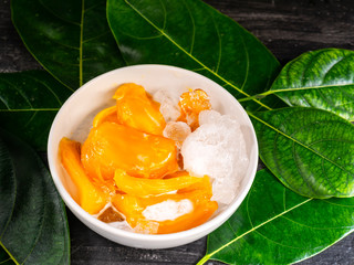A dessert, jackfruit in syrup with coconut milk and ice in white bowl.