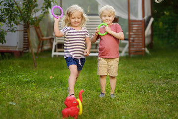 Cute little boy and girl playing in game throwing rings at summer outdoors