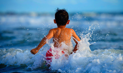 happy and crazy excited child running free towards sea horizon having fun on the beach playing...