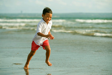 5 years old cute and happy child having fun on the beach playing free at the sea enjoying holidays running excited and cheerful in family travel vacation