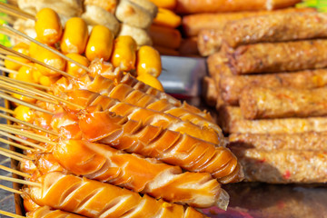 Sausages on wooden skewers, baked on the grill, lie on the table with a traditional Asian street food. Close-up