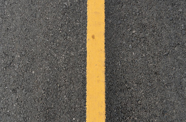 Top view surface of the asphalt road with yellow line.