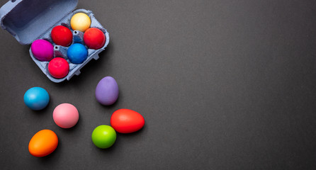 Easter eggs, pastel colors painted and a carton case, dark gray background