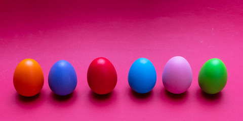 Easter eggs, pastel colors painted, standing in a row, bright pink background