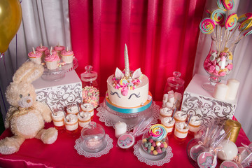 Candy bar for the first birthday for little baby girl. Sweet table and big unicorn cake