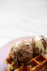 Traditional belgian waffle with lemon-chocolate icecream on pink plate, side view. Close-up. Copy space.
