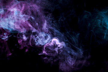 Translucent, thick smoke, illuminated by light against a dark background, divided into three colors: blue, green and purple, burns out, evaporating from a steam of vape.