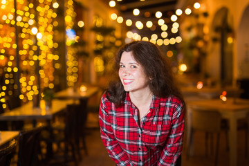 Nightlife, people and fun concept - Beautiful young woman poses near bright restaurant on the street at night