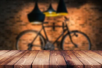 Poster Houten tafelblad op onscherpe achtergrond van coffeeshop (of restaurant) interieur en fiets aan de muur - kan worden gebruikt voor het weergeven of monteren van uw producten © คมน์วนัส อัศวจิตตานน