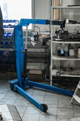 Vertical view of the tool for auto service. Blue crane for repairing the engine and gearbox of the car in the workshop for the restoration and maintenance of vehicles.