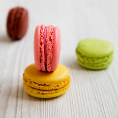 Sweet and colorful macarons on a white wooden background, side view. Selective focus. Close-up.