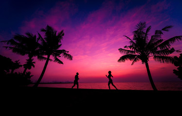 Fototapeta na wymiar Silhouette of couple on tropical beach during sunset on background of palms and sea