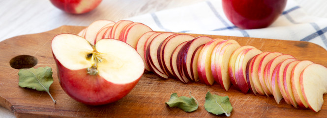 Slices of red apples on rustic wooden board, side view. Closeup.