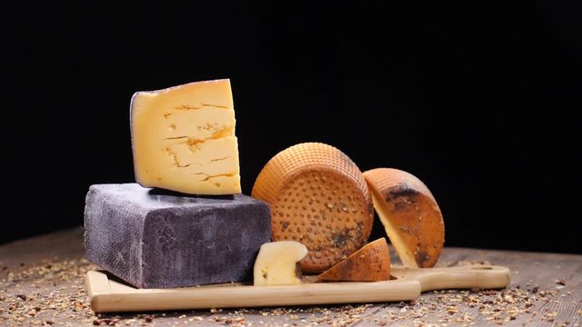 Food video. Luxury food concept. Cheese restaurant serving. Food art concept. Variety of hard cheese put on wooden board. Pods of red pepper falling down in slow motion. hd