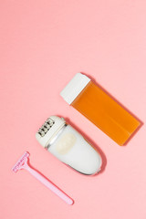 Beauty, depilation and hair removal concept - wax, spatula, epilator and safety razor on pink background. Top view.