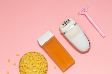 Beauty, depilation and hair removal concept - wax, spatula, epilator and safety razor on pink background. Top view.