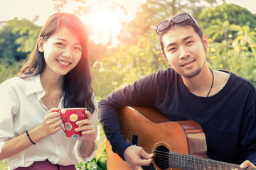 asian younger man and woman playing guitar 
