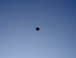 Balloon hot-air flies in the blue sky, far