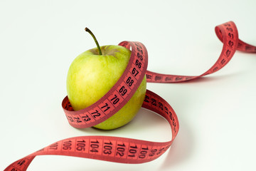 Green apple and measuring tape on white background