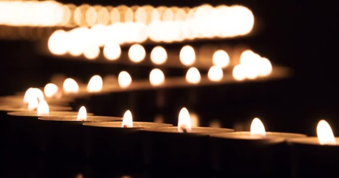 Serpentine Loops of Lights in the Dark. Winding line of burning candles stretching into the distance on a black background. The movement of air is waving lights