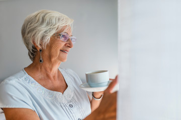 Senior woman at the window holding a cup of tea