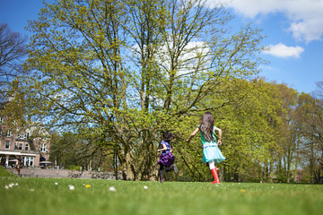 Fototapeta premium Cute Asian girl running around and playing in a big field surrounded by trees and nature in spring sunshine