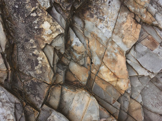 fractured rock strata as a background, cracked rock, stone texture, many cracks in the stone,...