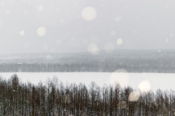winter landscape of forest lake in snowfall from a height