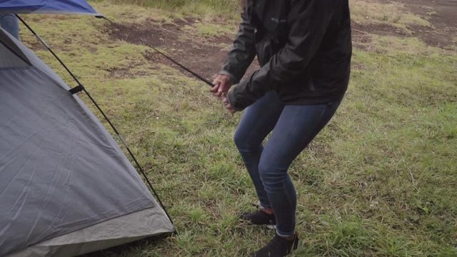 Slow Motion: Young Woman Setting Up Tent Outdoors on Windy Day