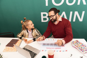 Fototapeta premium Cute fair-haired girl with bracelets on her hand smiling to her teacher