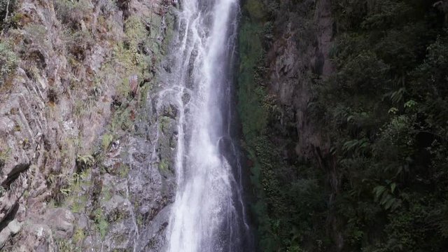 Slow Motion: Steep, Narrow Waterfall with People at the Pool at the Bottom