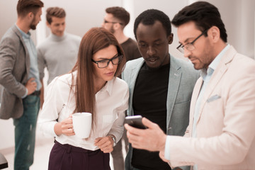 close up.a group of employees reading a message on a smartphone