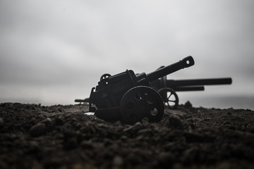 Battle scene. Silhouette of old field gun standing at field ready to fire. With colorful dark foggy...