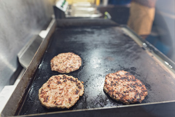 beef meat burger on the grill cooking inside the food truck van, street food cuisine inside the food street market festival for foodies