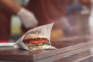close up of fast food gourmet burger with tomatoes and pickels  served at the food truck van, street food cuisine inside the food street market festival for foodies