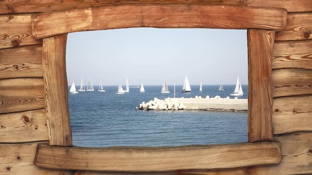 Seen from the window of a wooden cabin: a group of sailboats at sea, near a pier, ready for a competition (regatta).