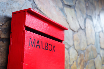 red mailbox with stone wall background.