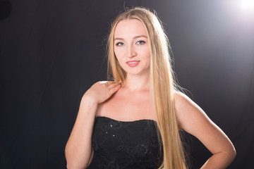 Naklejka premium Portrait of sexy blond elegant woman in black dress standing on black background