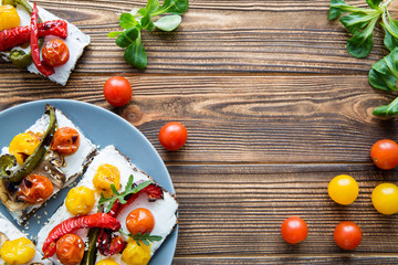 Tasty vegetarian breakfast on grey plate, creamy cheese, grilled tomatoes and mushtooms with sesame and green. Brown rustic table background. Copy space. 