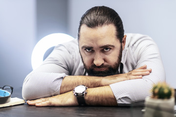 Obraz premium Dark-haired bearded man in a striped shirt feeling tired