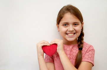 girl on a light background with a red plush heart in her hands