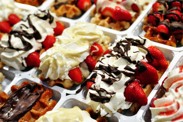 Assortment of desserts with ice cream and strawberry in plastic cups on street market