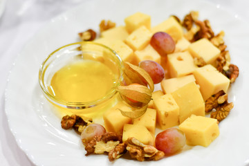a lot of types of cheese (Parmesan, Gouda, Emmental cheese) with honey, walnuts and physalis. appetizer in a French restaurant, snack for wine. dish for banquet, menu for wedding