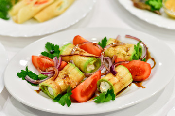 appetizer at the Italian restaurant: zucchini rolls grilled with mozzarella, tomatoes, red onions and balsamic vinegar, Italian cuisine, mediterranean diet, banquet