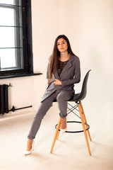 studio photo of a beautiful office woman, young company director sitting on a high chair on a white background