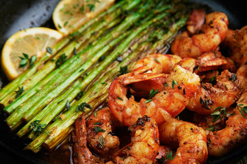 fried langoustines with asparagus decorated with lemon slices. roasted king prawns tiger shrimps with green garnish