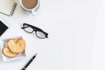 Cup of coffee with snacks and notebook on desk office with copy space, Top view