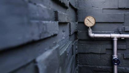 Water Pressure Gauge Meter on Pipes at Outside Building. Grey Brick Wall as background