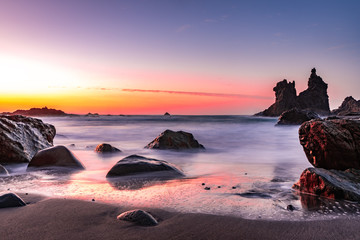 colorful sunset at beach with rocks in the sea on tenerife 